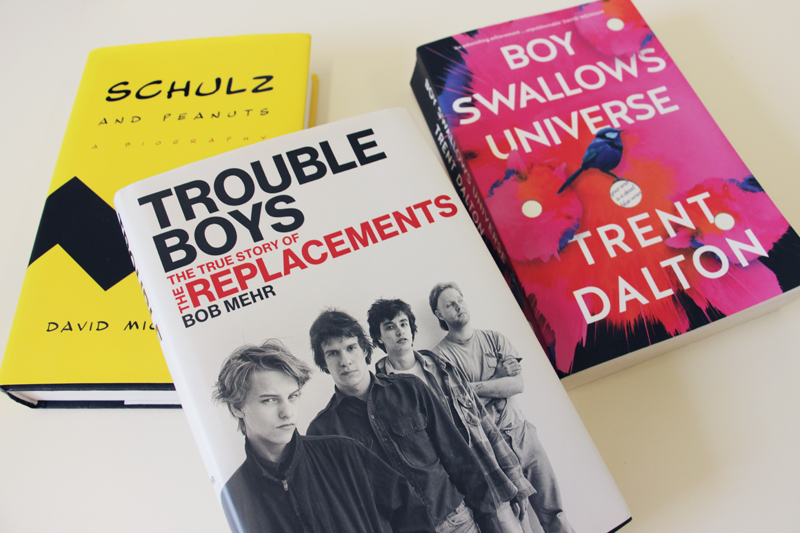 Book covers: "Schulz and Peanuts" by David Michaelis, "Trouble Boys" by Bob Mehr, and "Boy Swallows Universe" by Trent Dalton