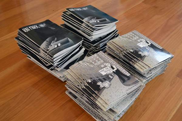 Four piles of Stuart McMillen comic books from crowdfunding drive: War on Drugs and Rat Park.