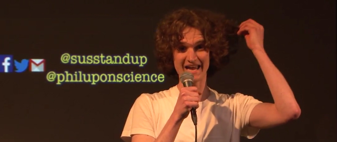 Stuart McMillen holding microphone performing stand up comedy