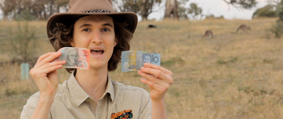 Stuart McMillen crowdfunding video wearing Akubra hat, holding money