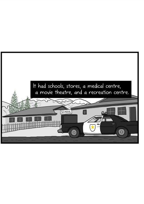 It had schools, stores, a medical centre, a movie theatre, and a recreation centre. Cartoon of police car parked outside small town building.