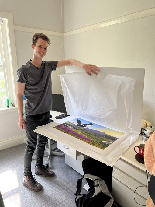 Stuart McMillen in his art studio, showing large art prints in a folio