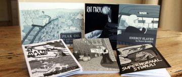 Six comic books by Stuart McMillen on a table