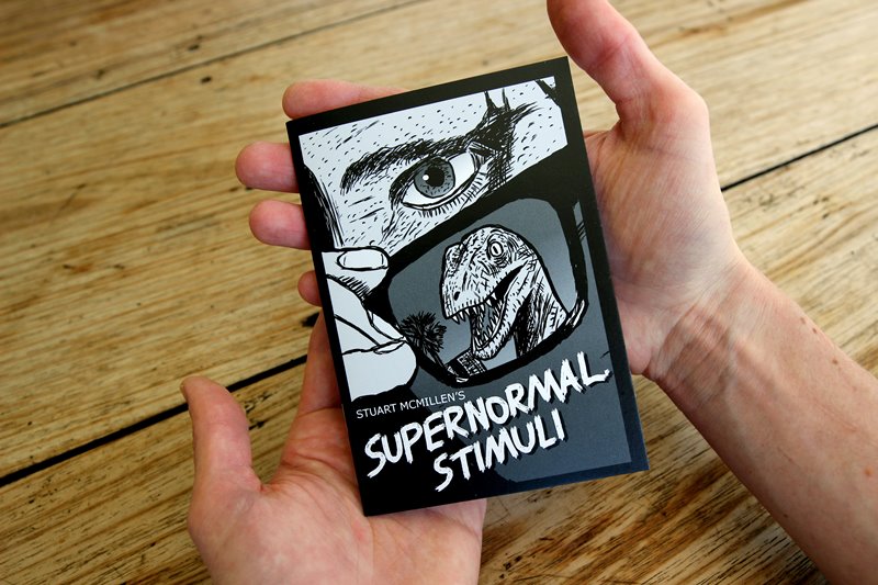 Supernormal Stimuli comic book front cover being held in a pair of hands