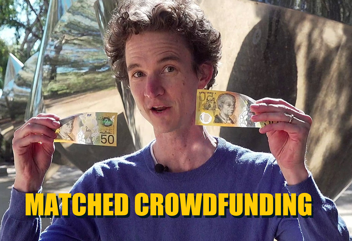 Stuart McMillen holding up two $50 notes, demonstrating matching crowdfunding